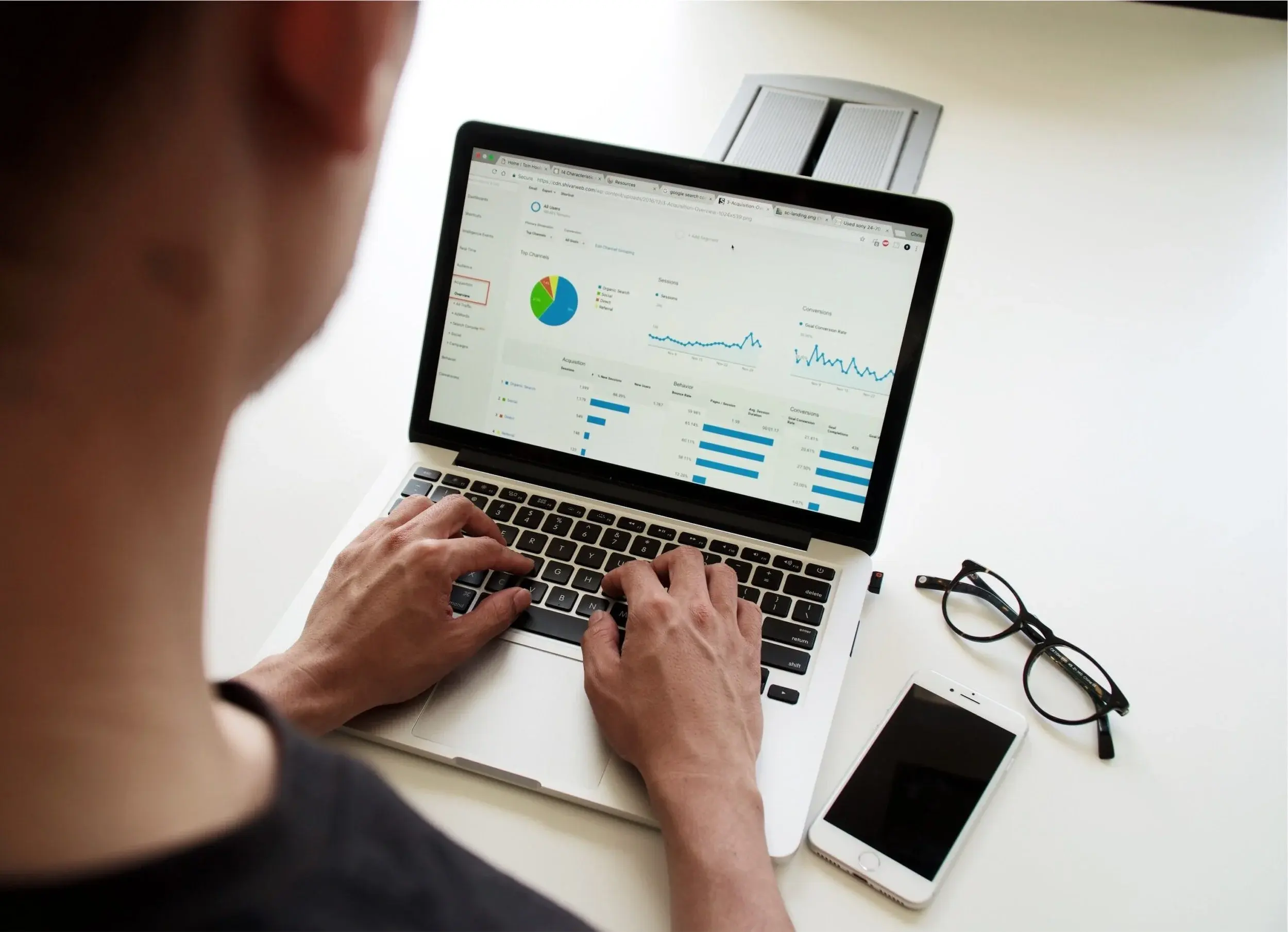A person reviews a web analytics dashboard of traffic sources and conversions on a laptop.