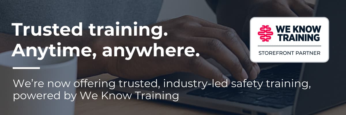 Email banner: hands typing on a laptop beside a white mug, dimmed behind the white headline Trusted training. Anytime, anywhere. and the line We’re now offering trusted, industry-led safety training, powered by We Know Training, with the We Know Training storefront partner badge at the right.